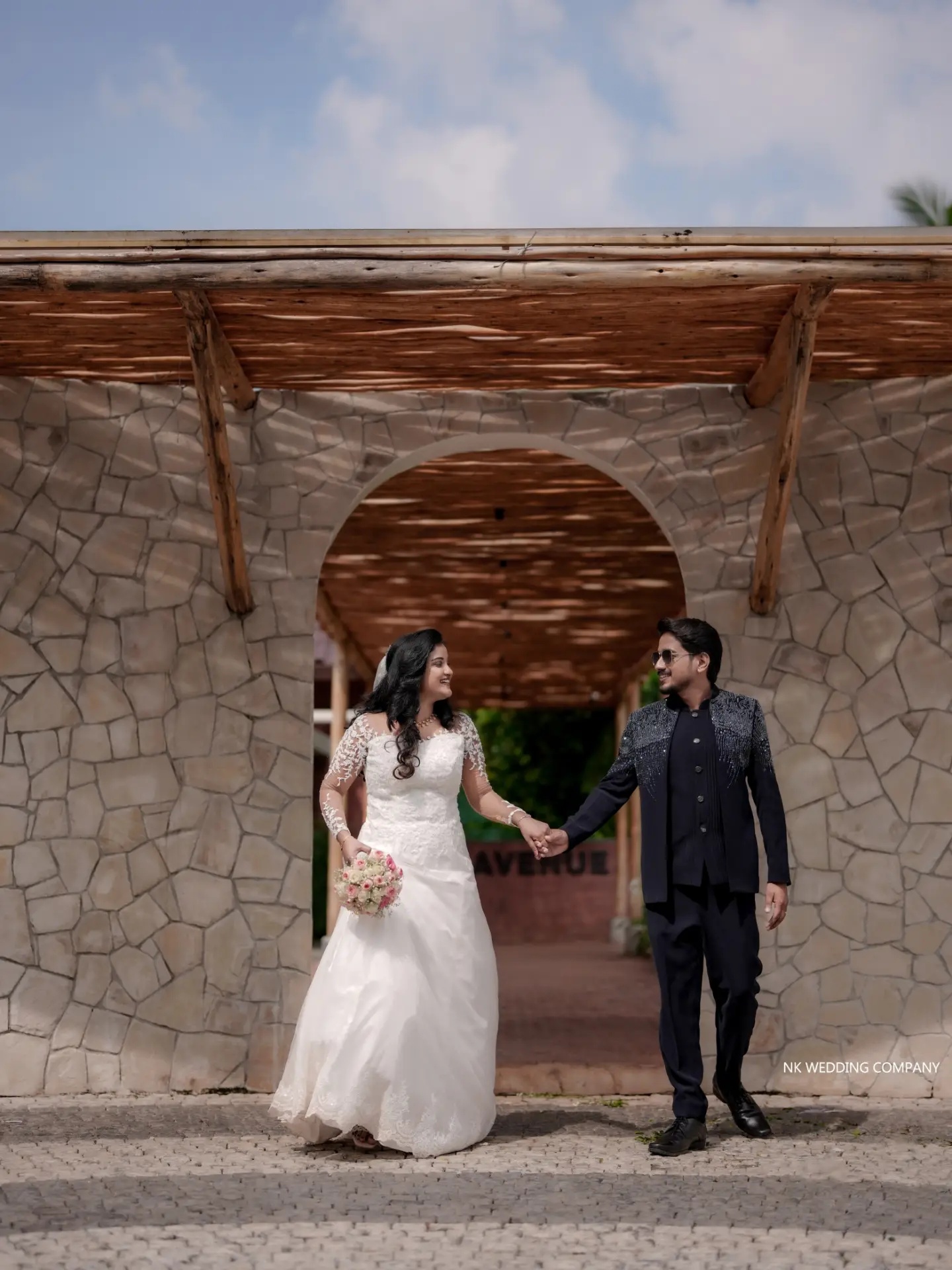 Wedding couple standing beneath a sculptural stone arch